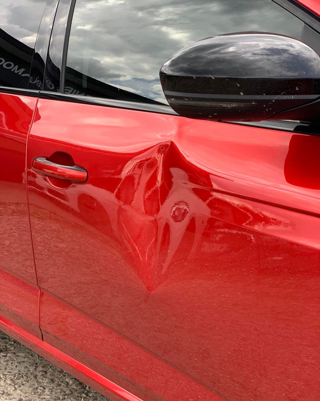 Wgniecenie drzwi czerwonego auta - przed naprawą